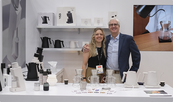 Two people standing behind a counter with Varia coffee-making equipment in a showroom setting.