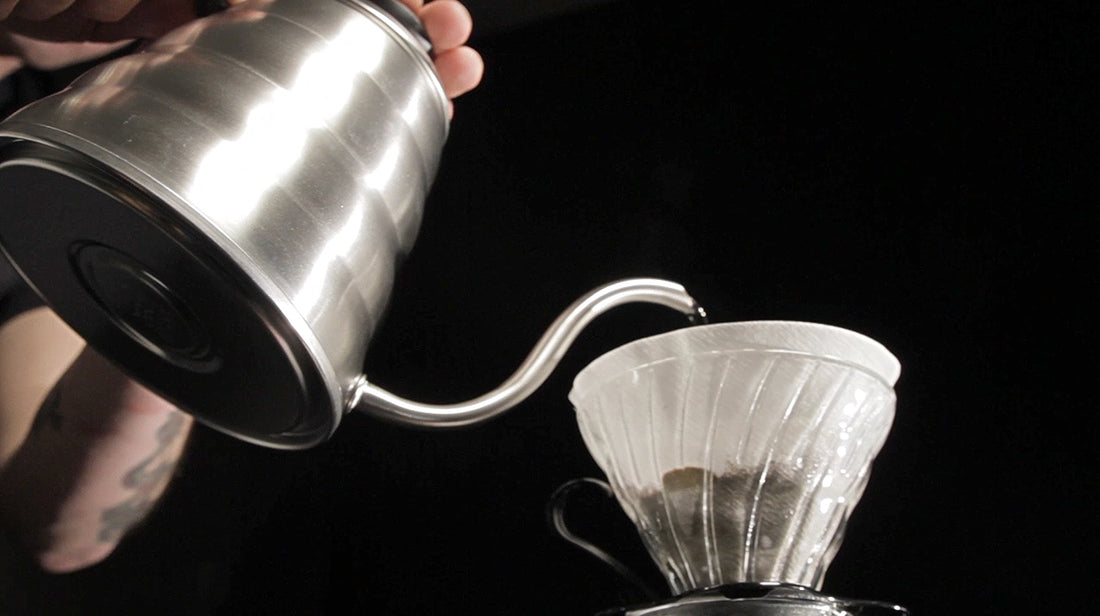 Water pouring from a kettle into a glass dripper